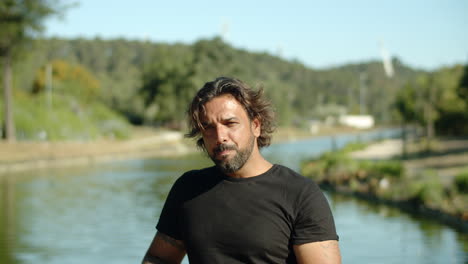 front view of happy athlete standing in park and drinking water