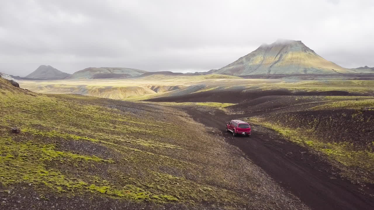 Red SUV Driving Through Icelandic Volcanic Landscape