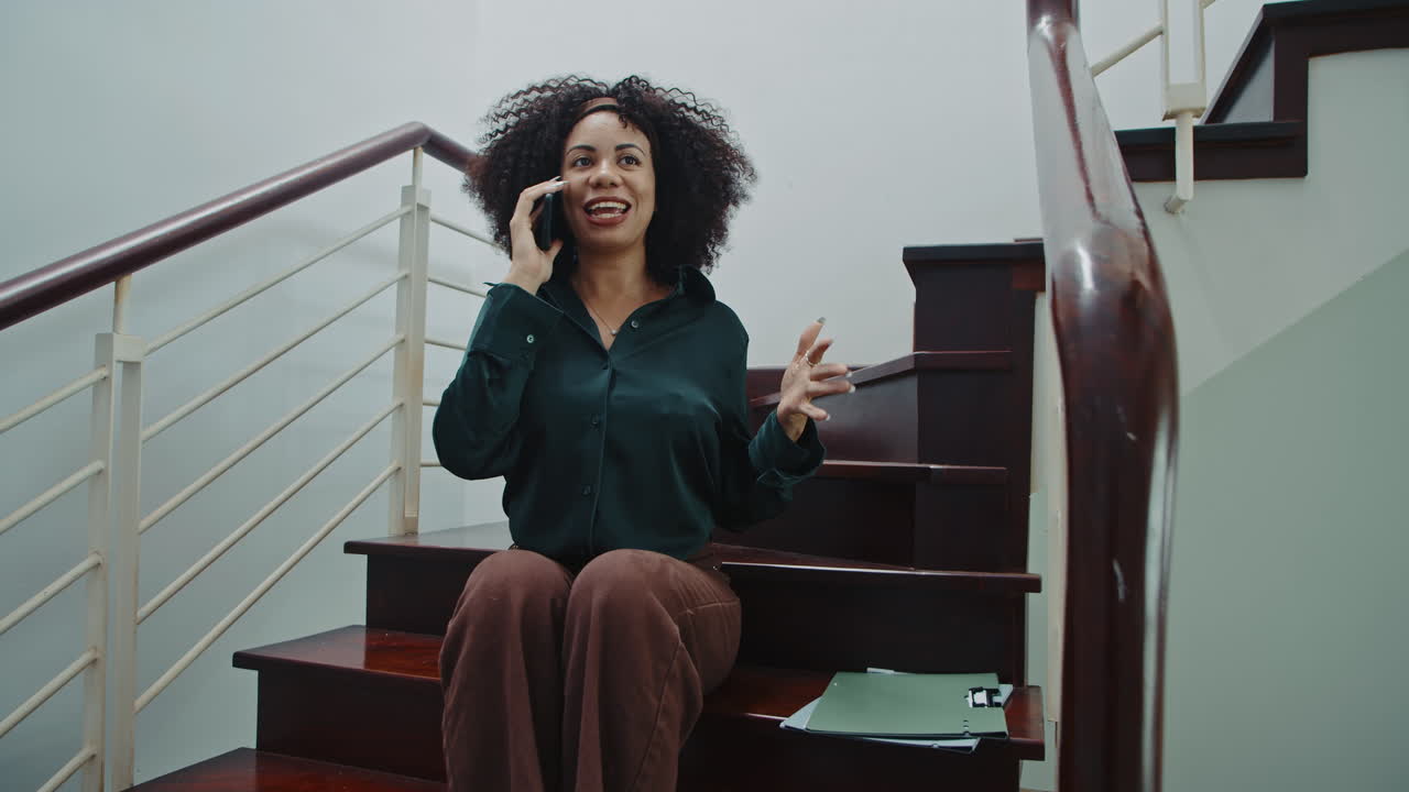 Excited Businesswoman Chatting with Friend on Smartphone Sitting on Steps