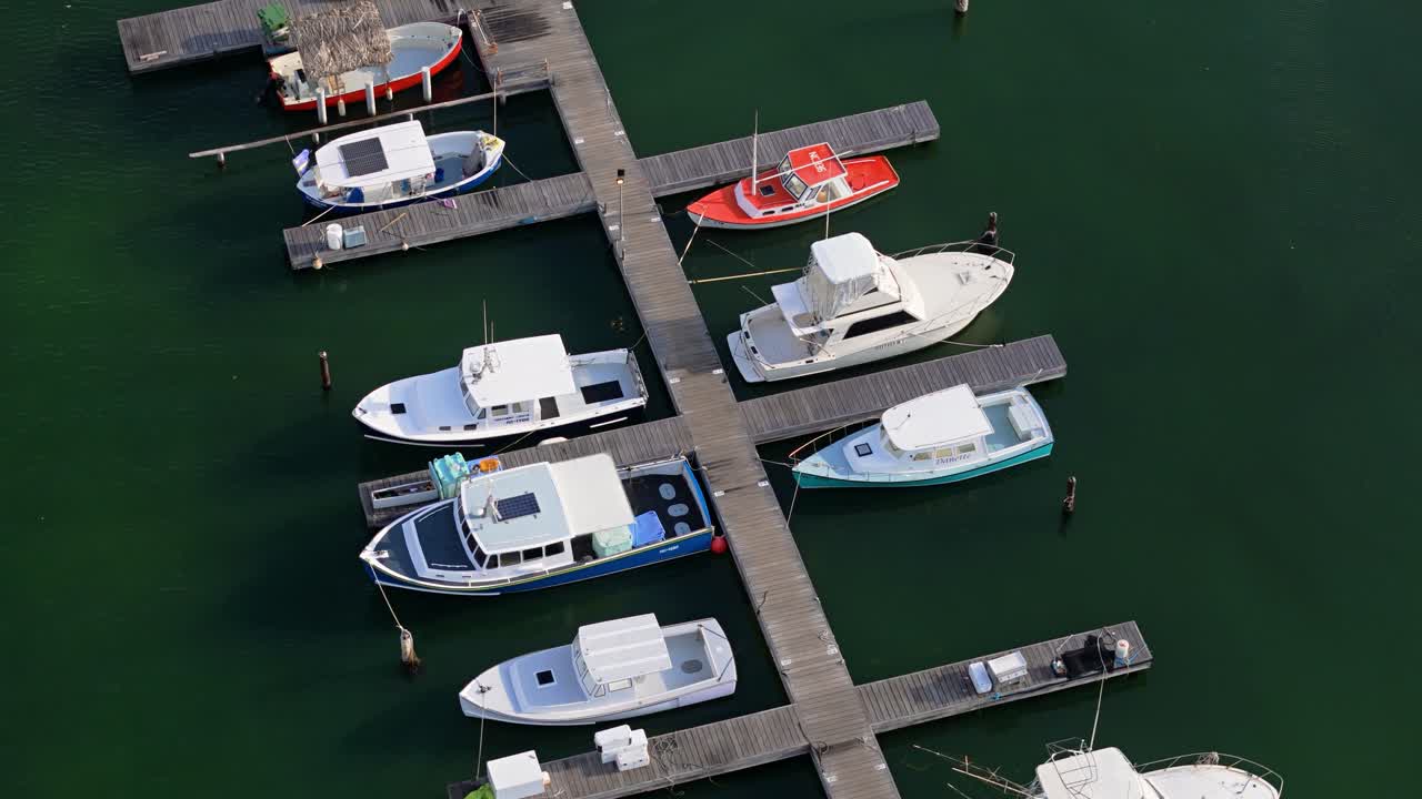 Drone flyver i kredsløb omkring træbroerne ved Spanskebugten, Curacao, mens fortøjede både vugger i vandet.