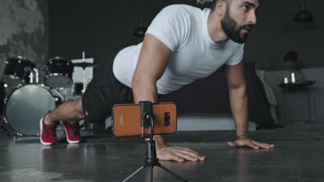 young man doing exercises in music studio and shoots it on the phone.