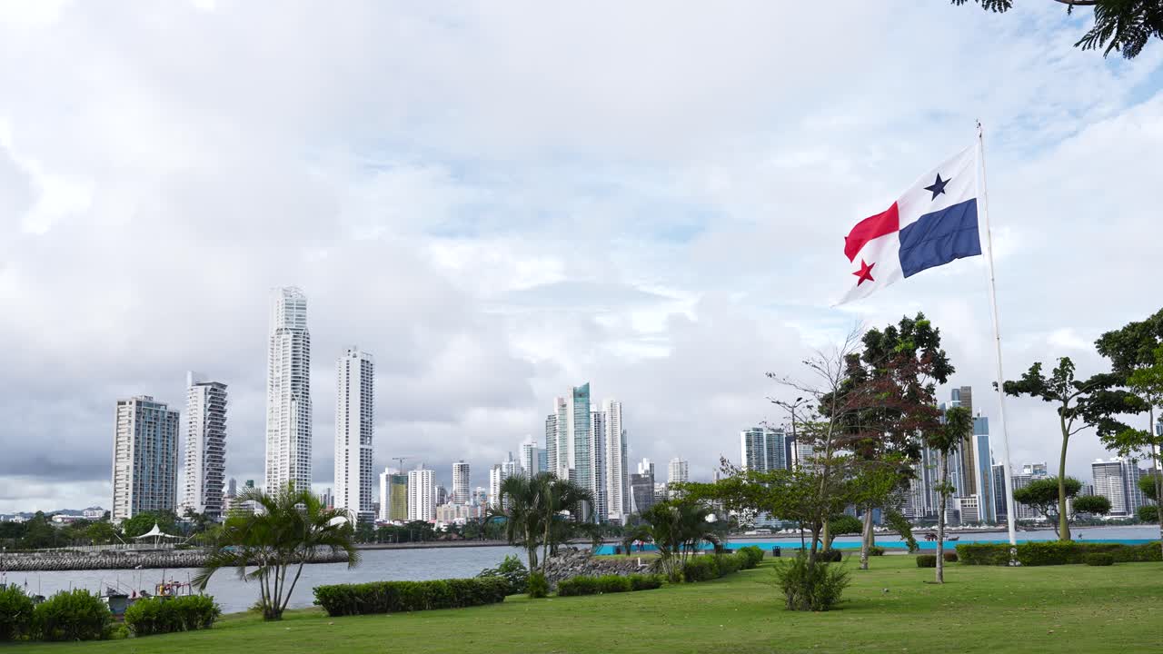 La bandiera nazionale di Panama sventola dolcemente al vento su uno sfondo di moderni edifici alti e grattacieli vicino alla costa