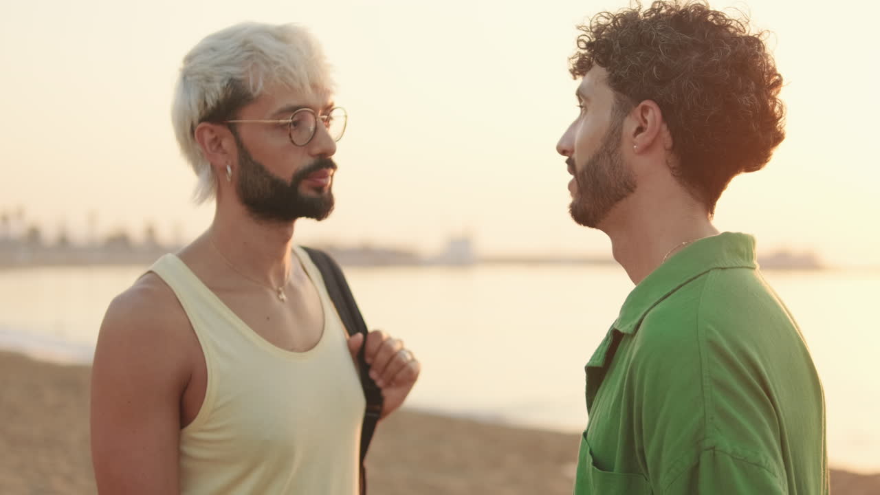 Due ragazzi che parlano e sorridono su una spiaggia al tramonto