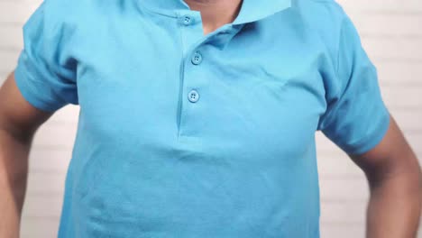 man buttoning a blue polo shirt