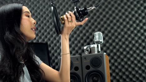 Asian-Teenager-Woman-wrapped-black-long-hair-sing-a-song-loudly-with-power-sound-over-hanging-microphone-condenser-and-equipment