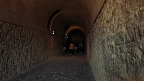 people walking through ancient stone tunnel