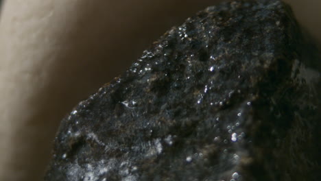 throwing water on a stack of hot stones in the sauna stove, slow motion extreme close up of water splashing and evaporating into steam, heating the sauna