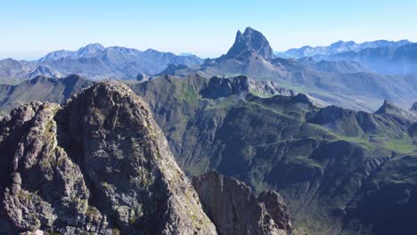 Vista-Aérea-Del-Pico-De-Anayet-Con-Un-Hombre-Parado-En-La-Parte-Superior-Vista-De-Drones-De-Los-Pirineos-Españoles-Y-Franceses-Durante-La-Mañana-La-Cordillera-Y-El-Lago-De-Anayet