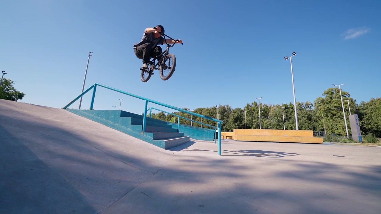 Rider BMX che salta giù dalle scale in uno skatepark all'aperto