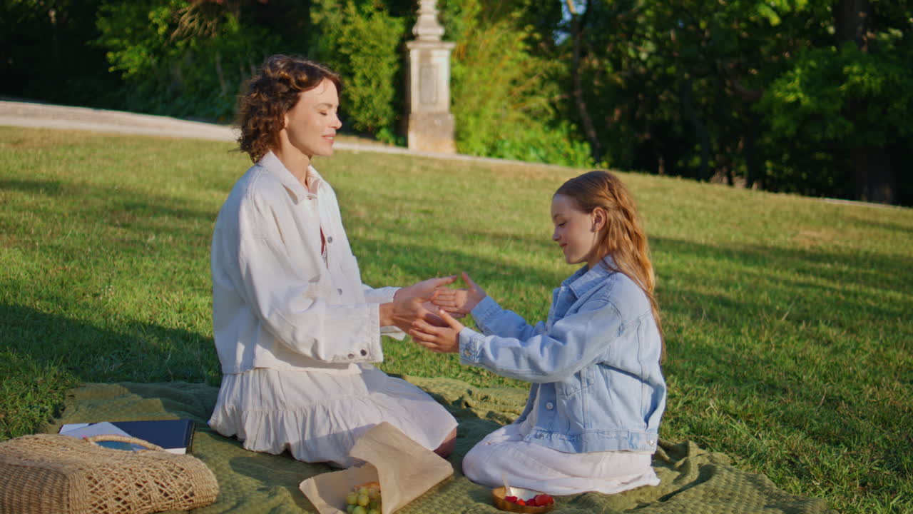 Positive family playing together at sunshine lawn. Mother kid clapping hands