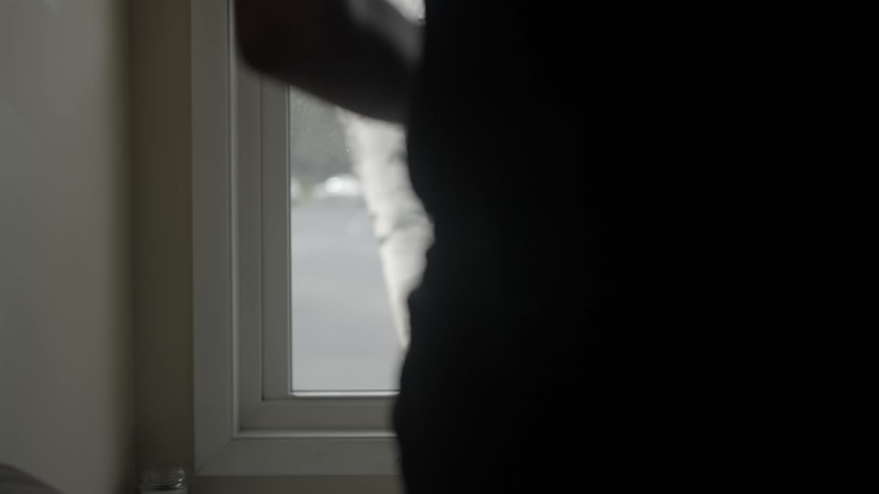 Person Sips Coffee Mug While Looking Out a Bright Residential Window