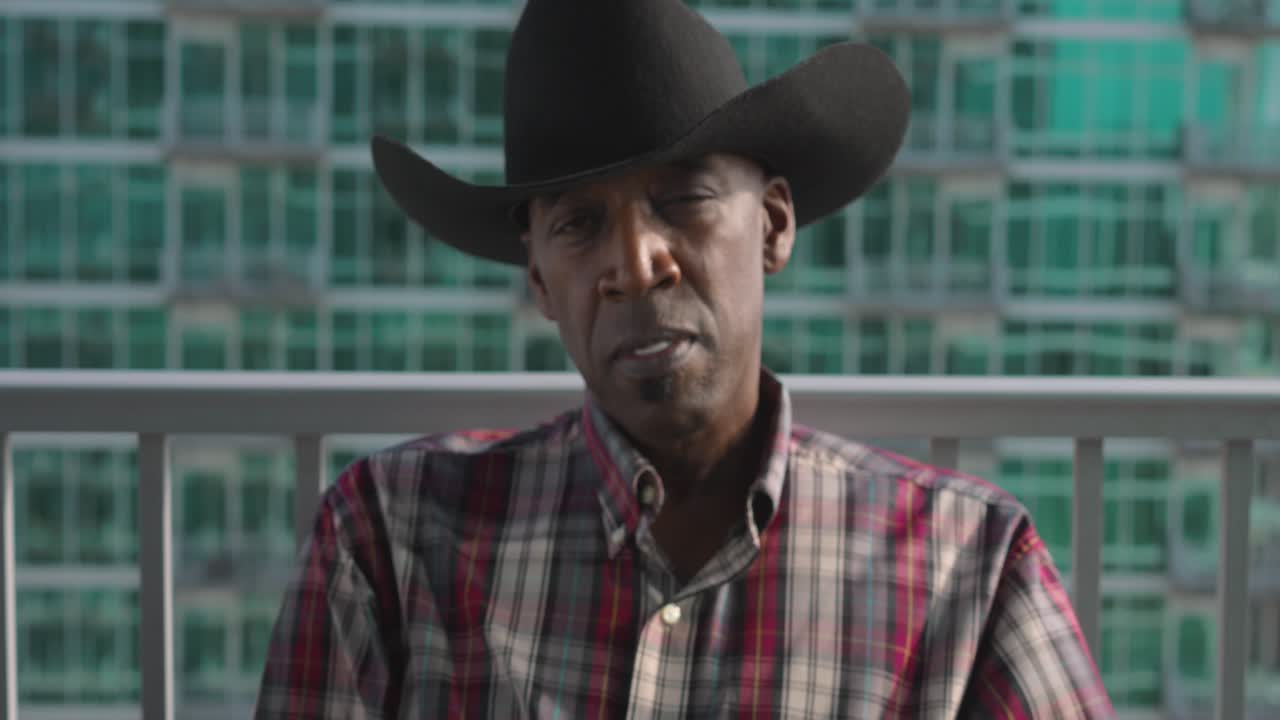 retrato de un hombre negro con sombrero de vaquero sonriendo