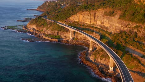 costa rocosa con carretera costera elevada en el puente del acantilado marino a lo largo de grand pacific drive, nueva gales del sur en australia