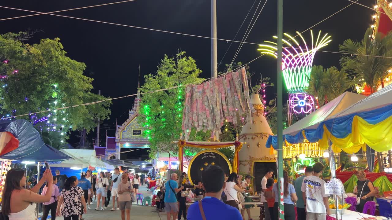 Colorful night market in Phuket, Thailand, with lively crowds, bright lights, and festive decorations under a clear night sky