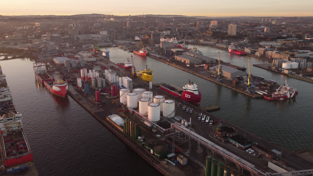 Aerial view of Aberdeen harbour and city at sunset - Aberdeenshire, Scotland, UK. Flight over harbour towards the city.
