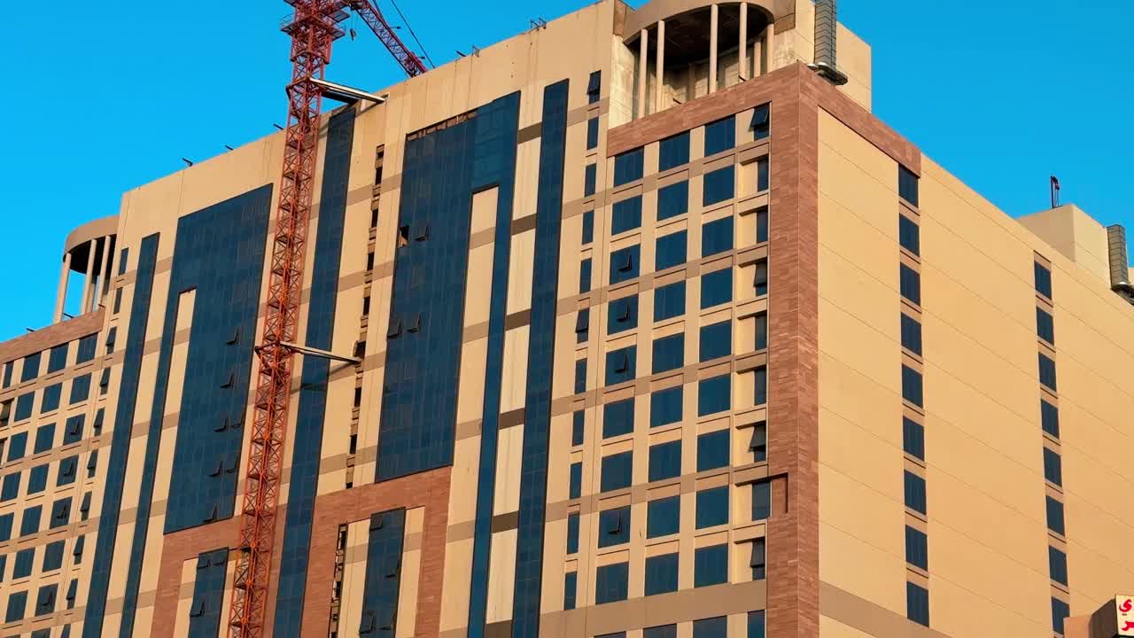 Detailed 4K shot of a modern high-rise with a crane, mid-construction. Ideal for architecture, urban growth, or real estate themes.
