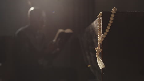 rosary beads and african-american clergyman reading bible on background