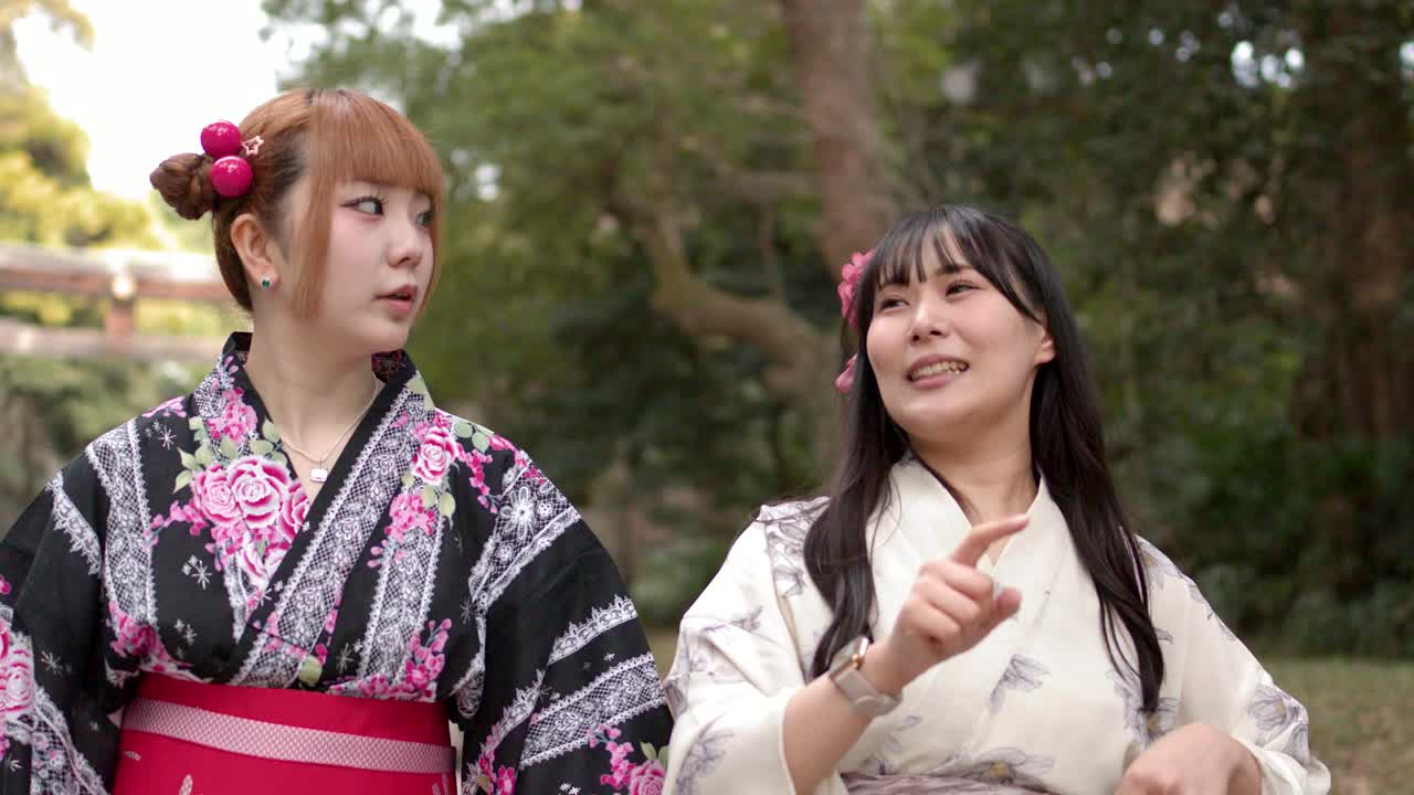 Due donne giapponesi che indossano yukata tradizionali camminano e parlano fuori da un santuario shintoista a Tokyo