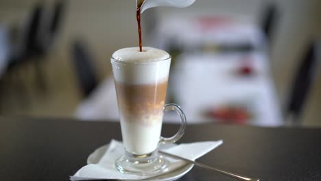 preparando café con leche en una cafetería, terminando de verter el café