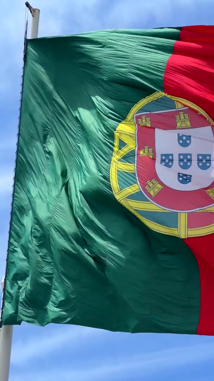 Portugals flagga vajar i vinden mot en blå himmel