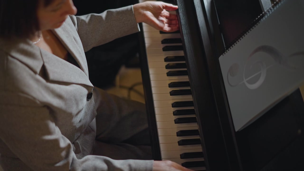 Ovenfra: Hvid pianistmentor forbereder sig ved keyboardet, blazerklædt instruktør tjekker noder og holdning, stille prøve med eftertænksomt udtryk og blød indendørs belysning, professionel undervisning