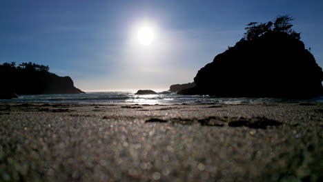 very low angle in the sand with sea stacks and waves crashing in the distance