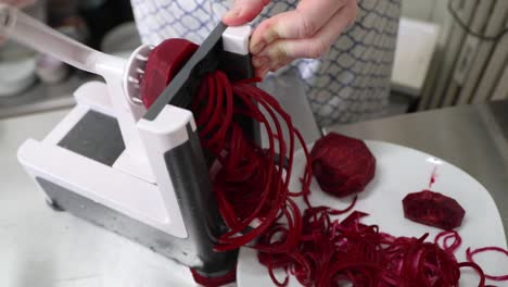 shredding beetroot in the kitchen with a rotary shredder - close up, slow motion