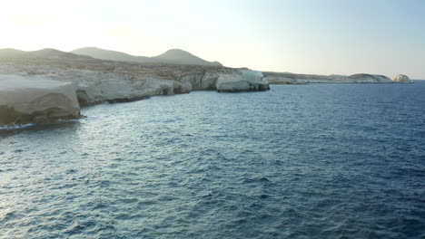 smooth cinematic aerial drone footage of sarakiniko beach with a person walking in milos island, greece at sunset in 4k