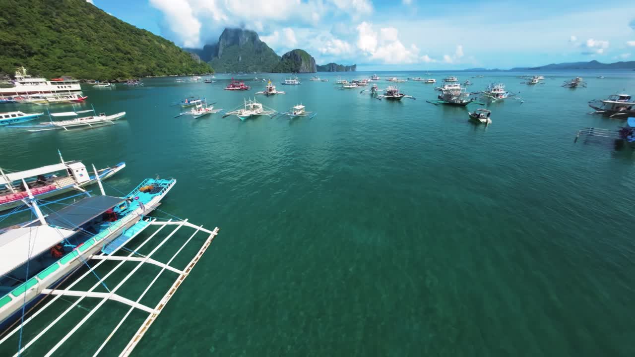 Captured in the serene waters of El Nido, Palawan, this photo showcases the stunning turquoise hues of the beach dotted with traditional outrigger boats and a lone kayak.