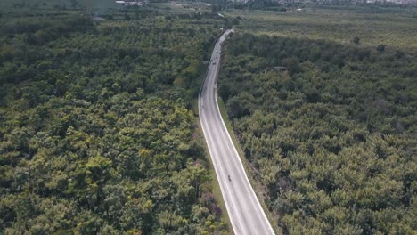 Aerial-drone-view-of-a-street-in-the-middle-of-the-forest-revealing-a-volcano-in-Guatemala