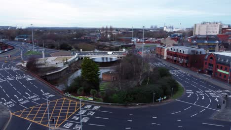 Aerial-early-morning-city-street-traffic-commuting-intersection-lanes-crossing-curved-river-pan-right-low-angle