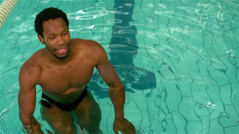 fit man cycling in the pool and crossing his arms
