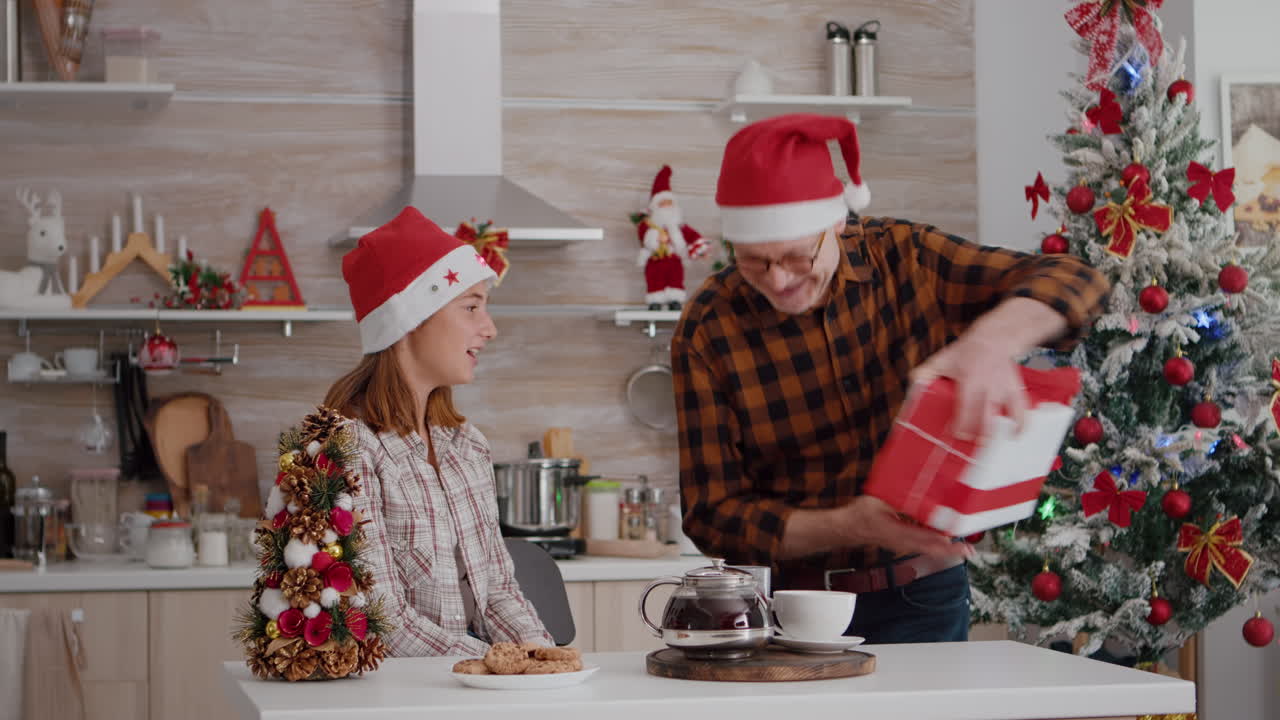 abuelo sorprende a la nieta con un regalo de regalo en la cocina decorada de navidad