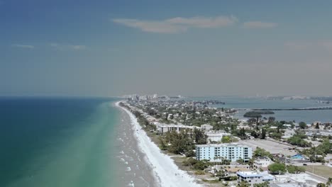 Drone-4K-high-over-white-sand-beach,-Clearwater-Florida-in-distance
