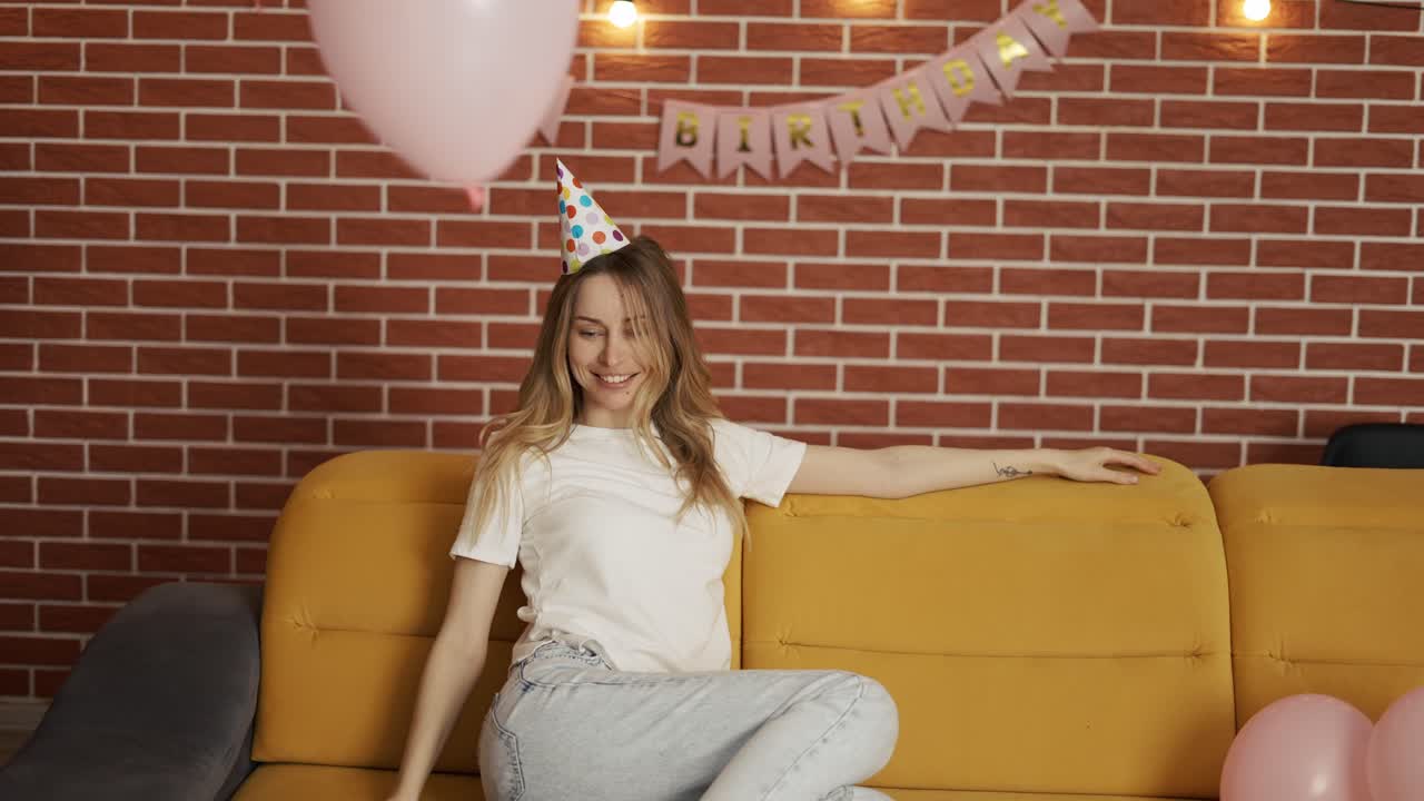 mujer con sombrero de cumpleaños en una habitación decorada jugando al globo