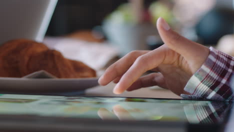 mano de mujer de cerca usando una tableta digital navegando por las redes sociales en línea con un dispositivo de pantalla táctil relajándose en una cafetería desplazándose sin fin
