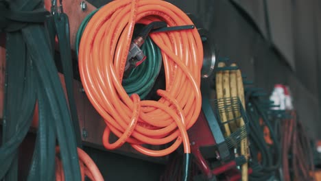 orange-hose-hangins-on-the-wall-full-of-other-hoses-with-different-dimensions-and-different-sizes