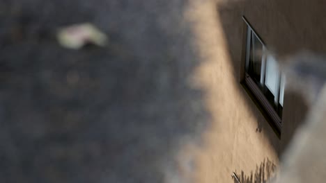 Perspective-of-a-window-and-wall-being-reflected-in-a-puddle-on-the-ground-after-a-rain-storm-with-rain-droplets