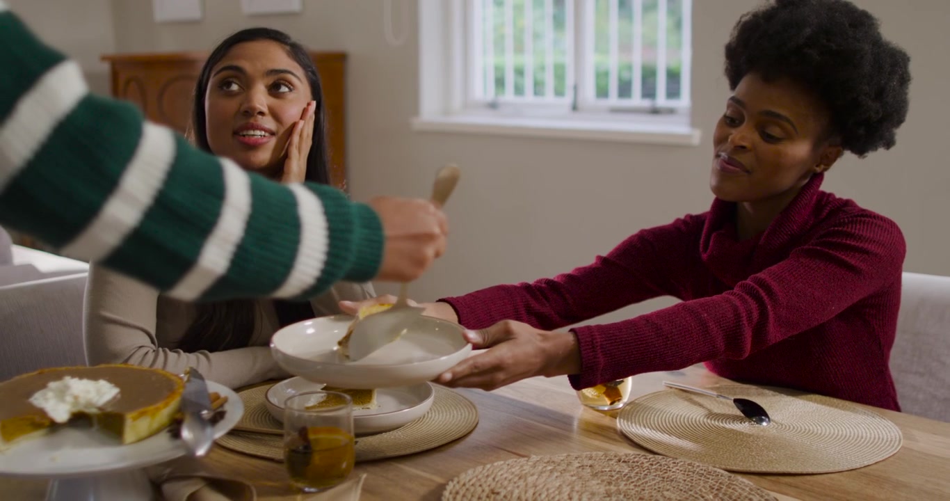 African American mom and daughter watching server serving pumpkin pie slice at table for dessert