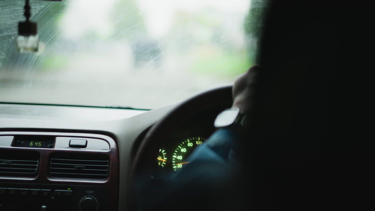 Overcast weather shapes cityscape during commute, Raindrops on windshield obscure view of rainy urban streets, Grey skies and rainbathed roads create somber atmosphere for city transit