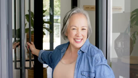 청바지 셔츠 를 입은 회색 머리 를 가진 아시아 여성 이 따뜻 한 미소 를 짓고 있다