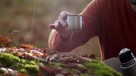 Touristischer-Mann,-Der-Heißen-Tee-Oder-Kaffee-Im-Wald-Trinkt,-Nahaufnahme-Der-Hand,-Die-Thermobecher-Hält