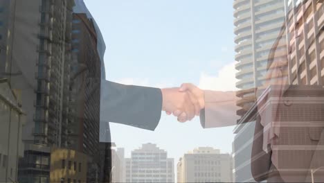 digital composition of business people shaking hands against tall buildings in background