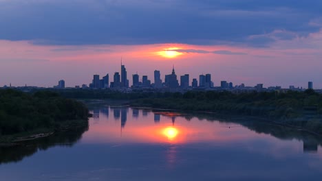 vistula river with downtown district skyscrapers in background at sunset, warsaw, drone shot