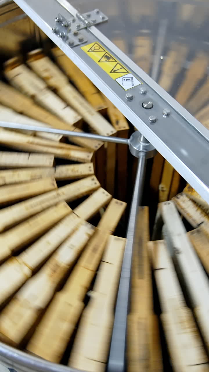 Centrifuge device pumping honey from cells. Honey extractor is spinning with frames with honeycombs. Process of getting honey from honeycomb. Vertical video