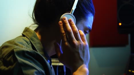 ingeniero de audio masculino escuchando auriculares mientras mezcla sonido