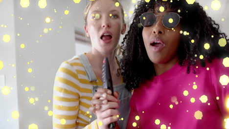 animation of yellow lights over two diverse teenage girls miming singing with tv remote control