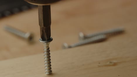 close up of electric screw driver drilling out screw of wooden board