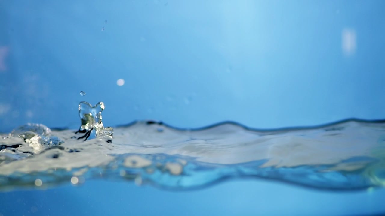 A shining water drop clings to a smooth surface, reflecting light in a macro view that showcases the transparency and beauty of nature.