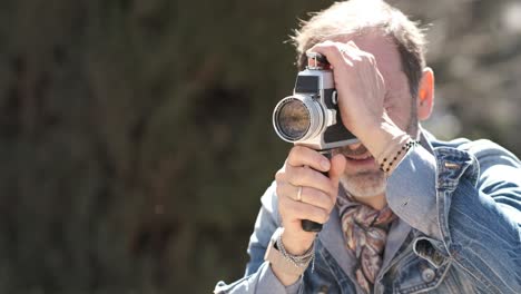 Mature man shooting video in city park with vintage camera